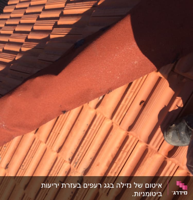 רעפים כתומים על גג עם רצועת בידוד אדומה